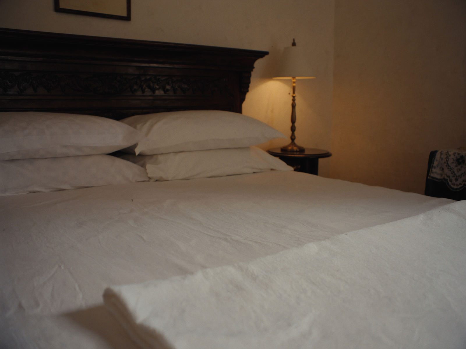 Neatly made king bed in a Deluxe Room at OPS Guest House, Dhulagori